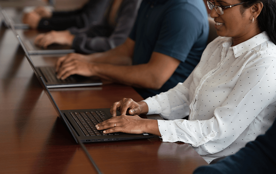 Gruppe aus Männern und Frauen, die mit Laptops an einem Besprechungstisch sitzen