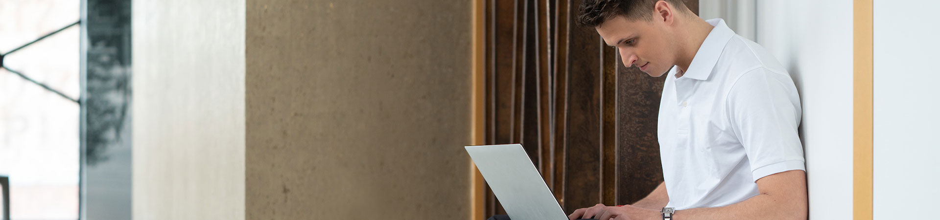 Junger Mann mit Laptop in einem offenen Geschäftsraum